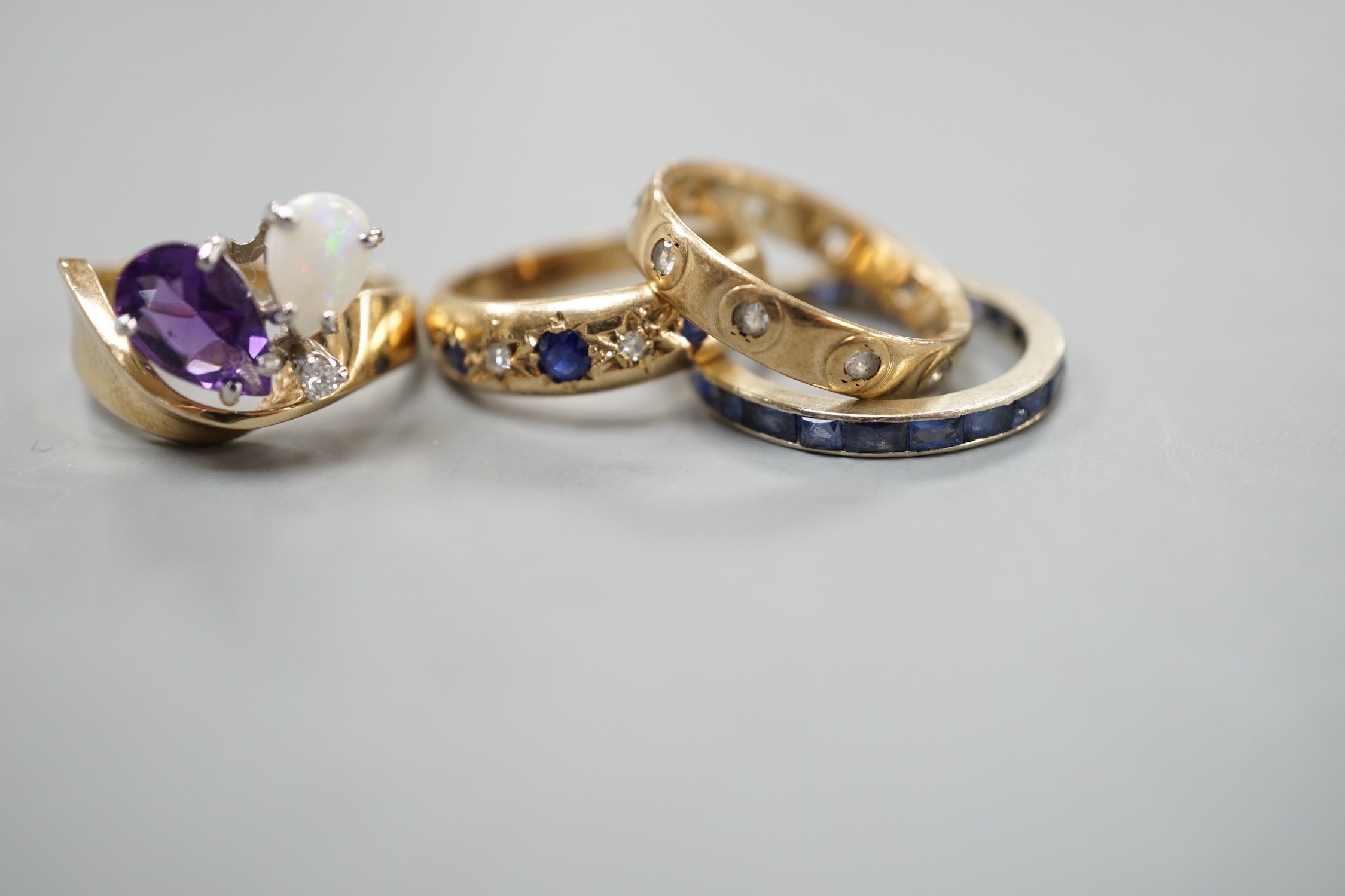 A 10k yellow metal, amethyst, white opal and diamond set dress ring, size N, gross weight 4.6 grams, two 9ct and gem set rings and a white metal and sapphire? set full eternity ring, gross weight 8.2 grams.